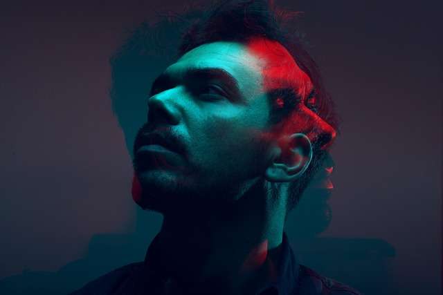 A moody portrait of a man with red and blue double-exposure lighting, symbolizing deep thinking and emotional intelligence.