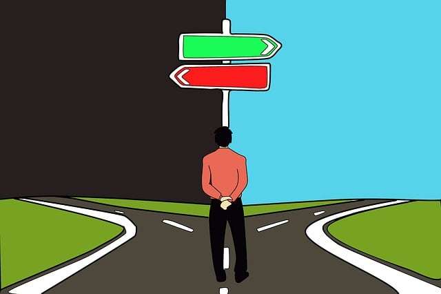 A man standing at a fork in the road under a signpost with green and red arrows, illustrating an early decision synonym or choice path.