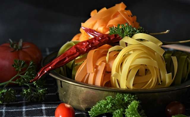 A bowl filled with colorful nest pasta, red chili pepper, and fresh tomatoes, emphasizing the role of a healthy diet in the How to Control Anger Inside Out Guide.
