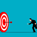 Businessman running toward a red target with an arrow, illustrating career opportunities and setting goals to choose the right career path.