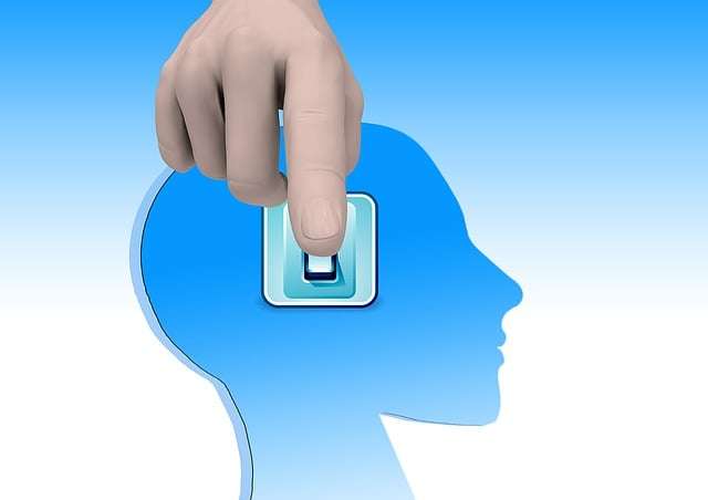 Graphic of a hand flipping a switch inside a blue human head silhouette, symbolizing how to stop caring what people think by changing your mindset.