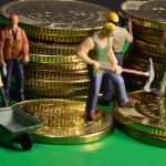 Miniature figurine workers laboring on stacks of gold coins, representing hard work and wealth building inspired by The Richest Man In Babylon.