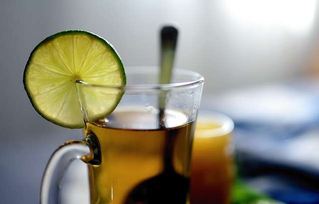 Glass mug of warm herbal lemon tea with a lime slice for antioxidants and reducing inflammation