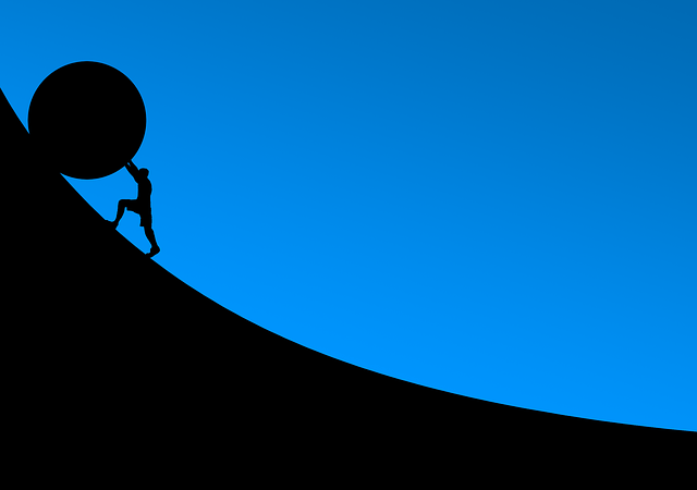 Silhouette of a person pushing a boulder up a hill representing personal responsibility and overcoming self-esteem challenges