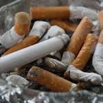 Glass ashtray full of extinguished cigarette butts, depicting how to quit smoking rapidly.