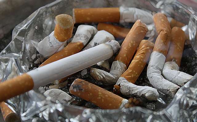 Glass ashtray full of extinguished cigarette butts, depicting how to quit smoking rapidly.