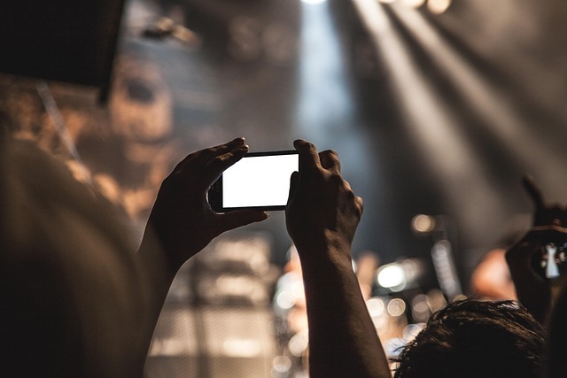 Hands holding up a smartphone at a concert, representing screen habit loops in a guide on how to get rid of masturbation addiction.