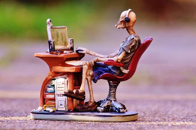 Miniature figurine of a skeleton sitting at a computer desk, illustrating long-term screen habits in an article on how to get rid of masturbation addiction.