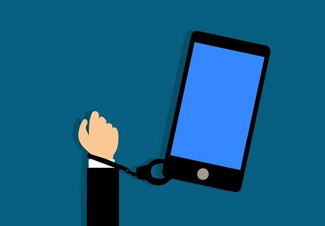 Vector graphic of a person's wrist handcuffed to a large smartphone screen, illustrating phone addiction and loss of self-control.